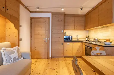 a kitchen with wooden cabinets and a table in a room at Cadin Apartment in Cortina dʼAmpezzo