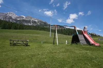 a playground with a slide and a bench in a field at Cadin Apartment in Cortina dʼAmpezzo