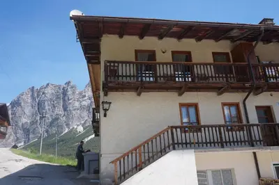 a man standing outside of a building with a balcony at Cadin Apartment in Cortina dʼAmpezzo