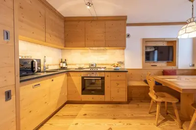 a kitchen with wooden cabinets and a wooden table at Cadin Apartment in Cortina dʼAmpezzo