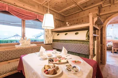 a dining room with tables and chairs and a fireplace at Aparthotel Panorama in Gais