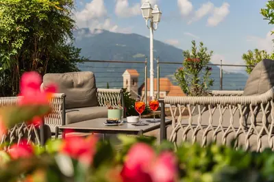 a patio with chairs and a table with flowers at Hotel Starkenberg in Schenna