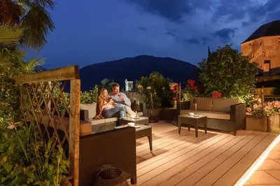 a man and woman sitting on a deck at night at Hotel Starkenberg in Schenna