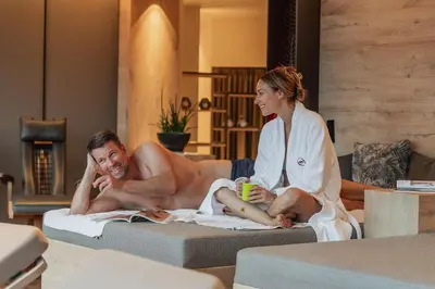 a man and a woman sitting on a bed in a room at Hotel Starkenberg in Schenna