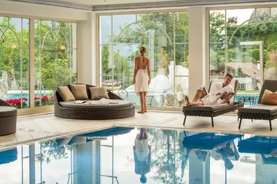a man and a woman standing in a living room next to a pool at Hotel Starkenberg in Schenna