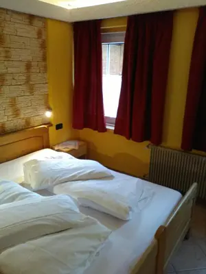 two twin beds in a room with a window at casa claudio-APPARTAMENTI IN CENTRO in Campitello di Fassa