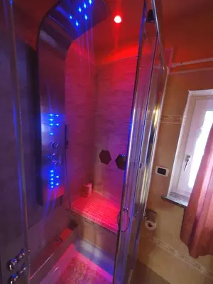 a bathroom with a shower with red and blue lights at casa claudio-APPARTAMENTI IN CENTRO in Campitello di Fassa