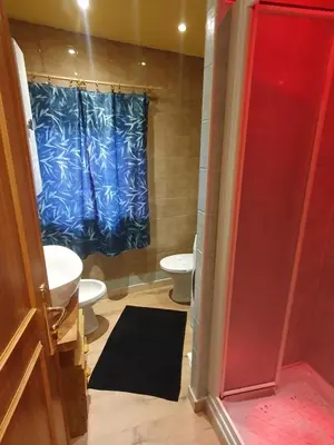a bathroom with two toilets and a blue shower curtain at casa claudio-APPARTAMENTI IN CENTRO in Campitello di Fassa