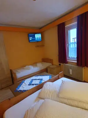 a small room with two beds and a television at casa claudio-APPARTAMENTI IN CENTRO in Campitello di Fassa