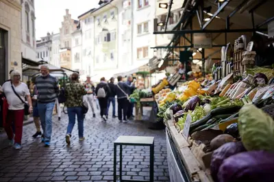 a group of people walking through a market with fruits and vegetables at Saltus in San Genesio Atesino