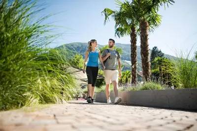 a man and a woman walking down a path at Hotel Dorner B&B in Lagundo