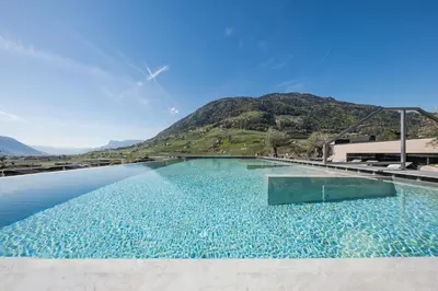 a large swimming pool with a mountain in the background at Hotel Dorner B&B in Lagundo