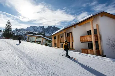 two people on skis in the snow near a building at Moseralm Dolomiti Hideaway in Nova Levante
