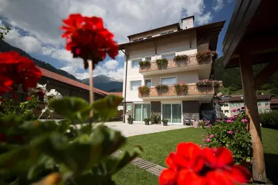 a building with red flowers in front of it at Appartamento Rose Di Bosco in Predazzo