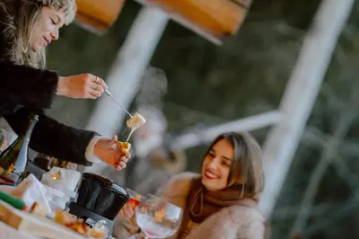 two women sitting at a table eating food at Nancy's Holiday Homes Dolomites in Rasùn di Sotto