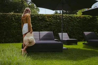 a woman standing next to a couch with an umbrella at Nancy's Holiday Homes Dolomites in Rasùn di Sotto