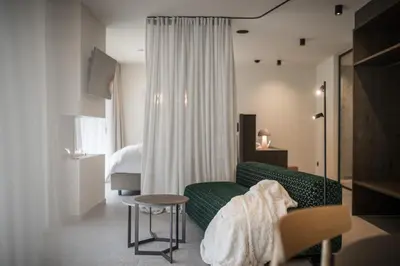 a living room with a green couch and a bed at Nancy's Holiday Homes Dolomites in Rasùn di Sotto