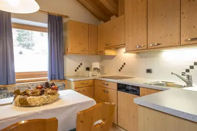 a kitchen with a table with a bowl of fruit on it at Ciasa Rosra in La Villa