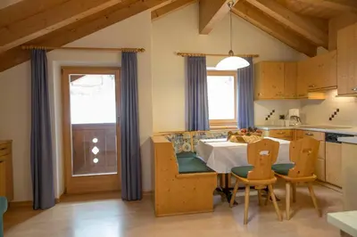a kitchen with a table and chairs and a kitchen with a window at Ciasa Rosra in La Villa