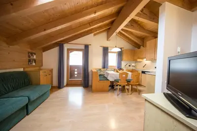 a living room with a couch and a dining room at Ciasa Rosra in La Villa