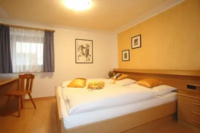 a bedroom with a large white bed with yellow pillows at Ciasa Rosra in La Villa