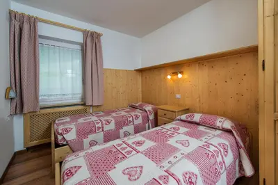 a kitchen and living room with a table and a red couch at Majon Vajolet - Apartments Luisa in Vigo di Fassa