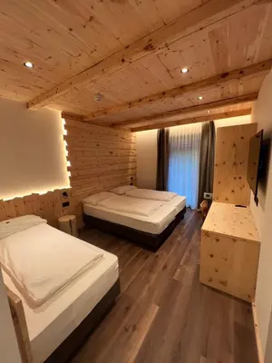 two beds in a room with wooden ceilings at Hotel De Fronz in Soraga