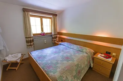 a small bedroom with a bed and a window at Hotel De Fronz in Soraga