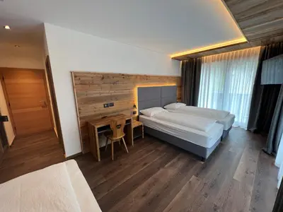 a bedroom with two beds and a table and a desk at Hotel De Fronz in Soraga