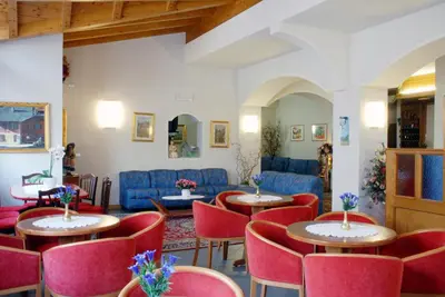 a room with tables and chairs and blue furniture at Hotel Sass Maor in Fiera di Primiero