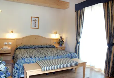 a bedroom with a bed and a bench in it at Hotel Sass Maor in Fiera di Primiero