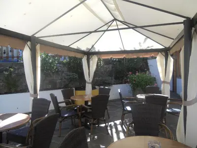 a patio with tables and chairs under a tent at Hotel Sass Maor in Fiera di Primiero