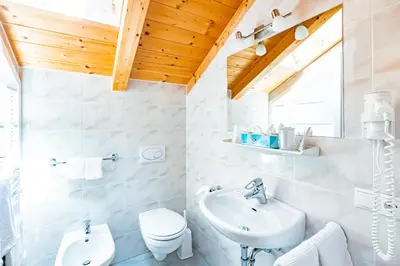 a white bathroom with a sink and a toilet at Gasthof Teiser Stern in Funes