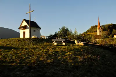 a church on top of a hill with a cross at Gasthof Teiser Stern in Funes