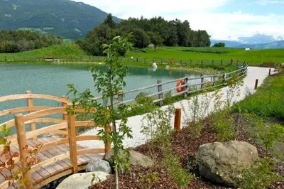 a wooden bridge over a lake with a fence at Gasthof Teiser Stern in Funes