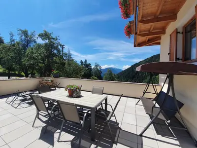 a patio with a table and chairs on a balcony at Mesnerhof in Lauregno