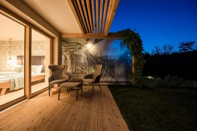 a bedroom with a bed and two chairs on a deck at SOFTALPIN Garden Suites in Appiano sulla Strada del Vino