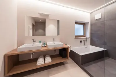 a bathroom with two sinks and a tub and a mirror at SOFTALPIN Garden Suites in Appiano sulla Strada del Vino