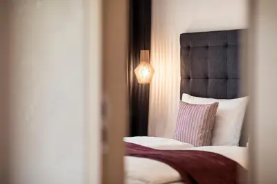 a bedroom with a bed with a black headboard and a lamp at SOFTALPIN Garden Suites in Appiano sulla Strada del Vino