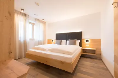 a bedroom with a large bed with white sheets at Residence Pitzinger in Falzes