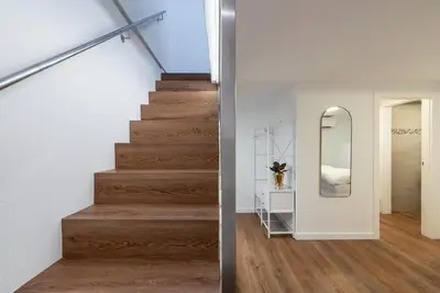 a staircase in a house with white walls and wood floors at Gasthof Hanni in Merano