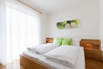 a bedroom with a bed with white sheets and green pillows at Gasthof Hanni in Merano