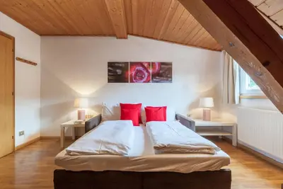 a bedroom with a large bed with red pillows at Gasthof Hanni in Merano