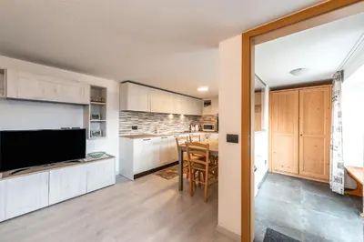 a kitchen with wooden cabinets and a table with a television at Appartamento Ciasa Ciaslir in Vigo di Fassa