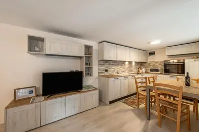 a kitchen with white cabinets and a table with a television at Appartamento Ciasa Ciaslir in Vigo di Fassa