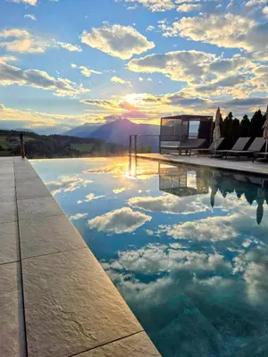 a pool with a reflection of the sky in the water at Hotel Avelina in Avelengo