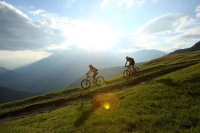 two people riding bikes on a grassy hill at Hotel Avelina in Avelengo