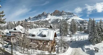 a house covered in snow in front of a mountain at Residence Chris Appart in Carezza al Lago