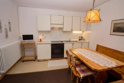 a kitchen with a wooden table and a kitchen with white cabinets at Residence Chris Appart in Carezza al Lago