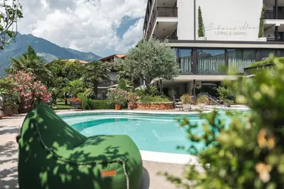 a swimming pool in front of a building at Hotel - Appartements Schmied Hans in Schenna
